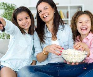 Featured image of smiling mother with two girls watching TV
