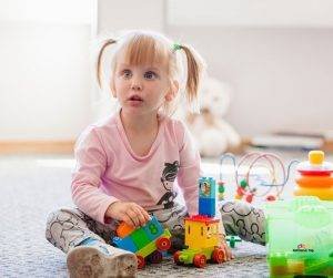 Featured image of little girl with ADHD playing with toys on floor