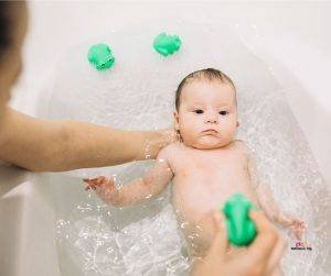 Featured image of mother bathing baby with green toy frogs
