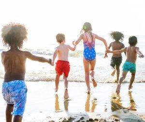 Featured image of children at the beach running towards water