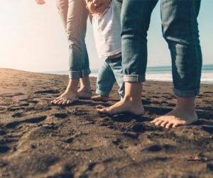Featured image of parents teaching baby to walk on beach
