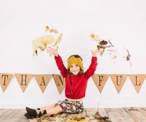 Featured image of smiling girl in red throwing leaves on thanksgiving